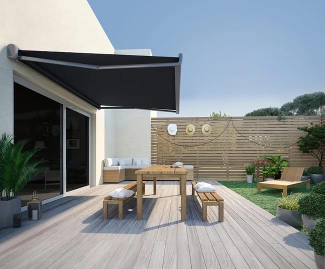 Store banne motorisé noir installé sur une terrasse moderne avec salon de jardin en bois – protection solaire élégante et pratique pour extérieur